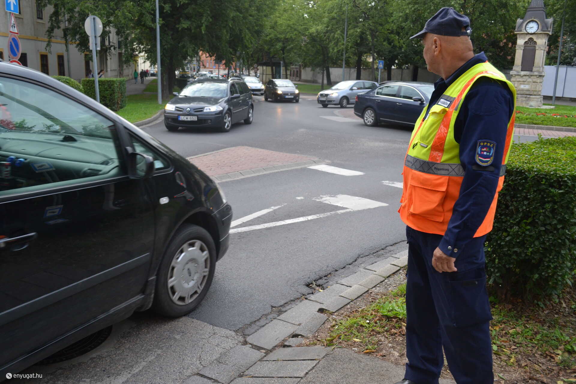 Polgárőr figyeli a forgalmat a Kossuth utcai körforgalomnál. A gyerekeknek segít.