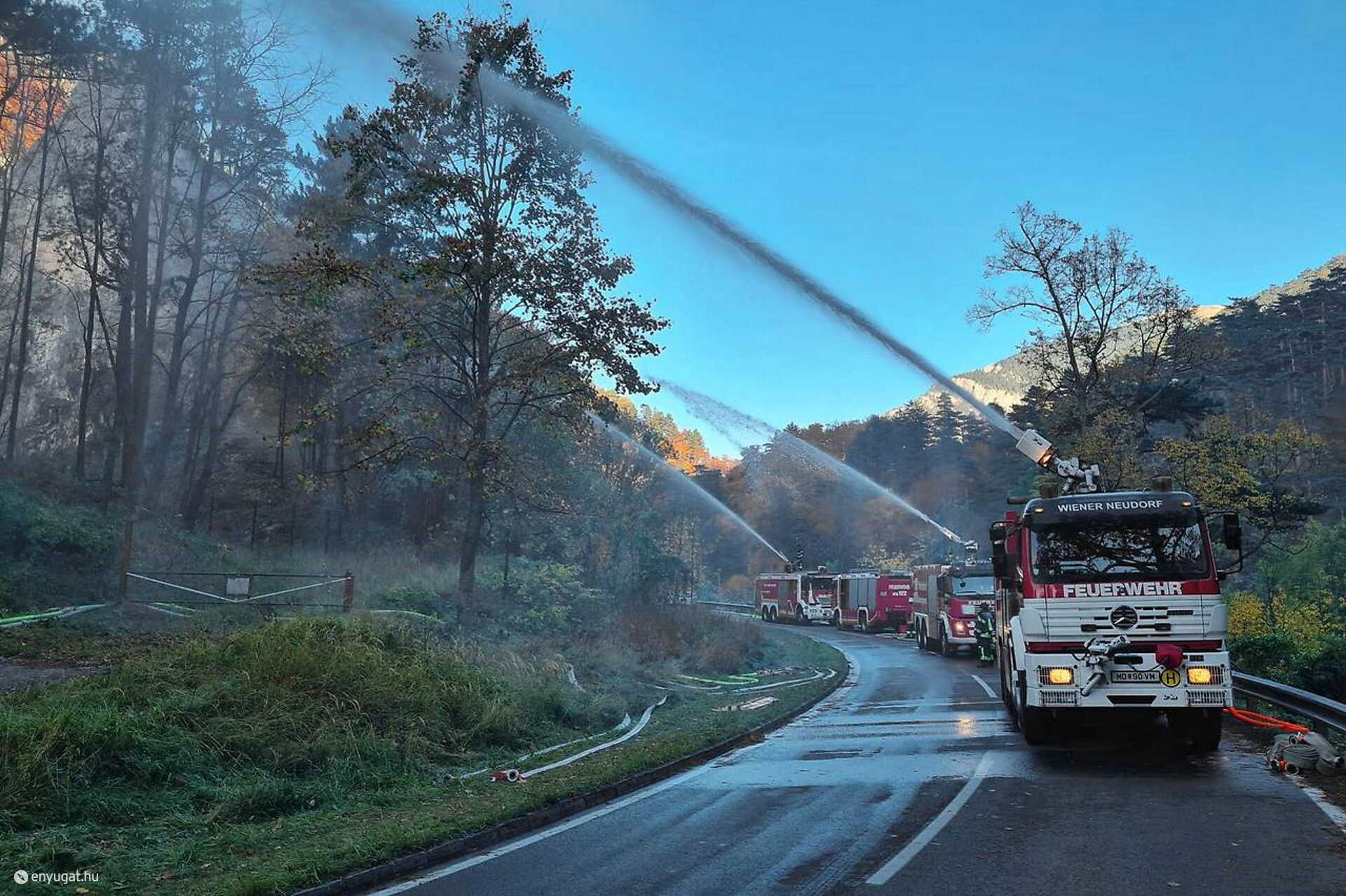 Tűzoltóautók vízfüggönnyel akadályozzák meg a tűz terjedését.